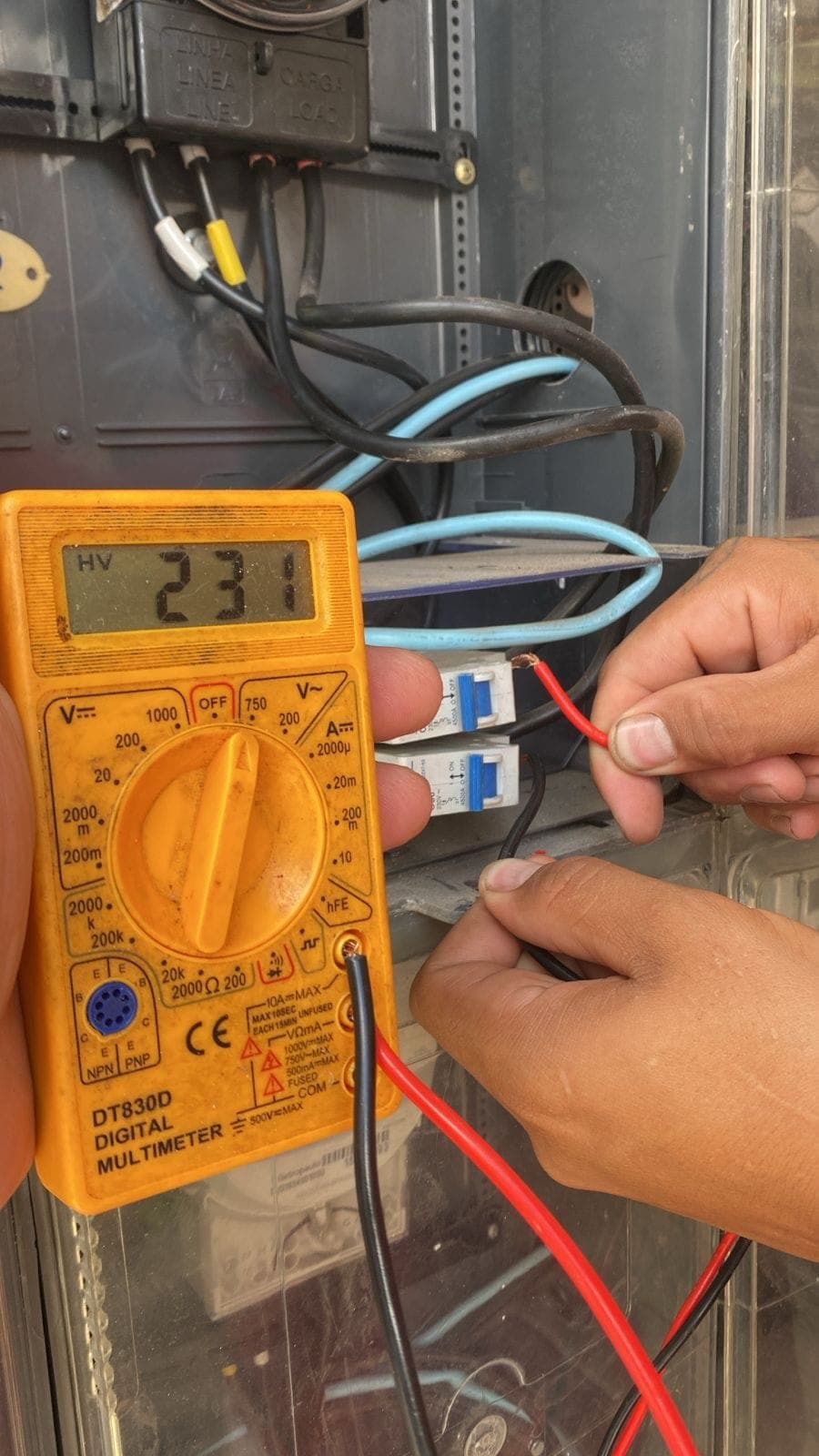 Medição de tensão com multímetro durante diagnóstico em quadro elétrico
