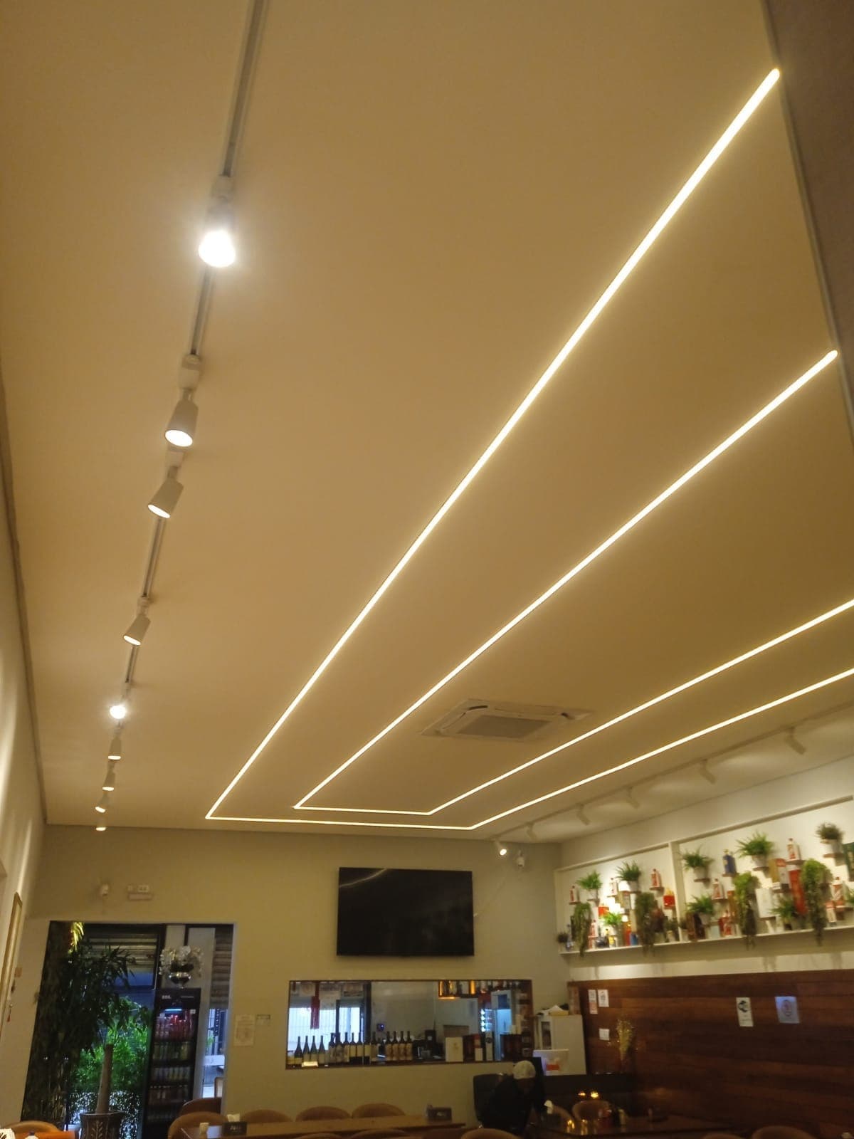 Trilho com spots e perfis de LED no teto de um restaurante